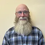 board member christopher olinger wearing plaid shirt wearing glasses