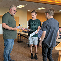 an instructor standing on the left and two students standing on the right