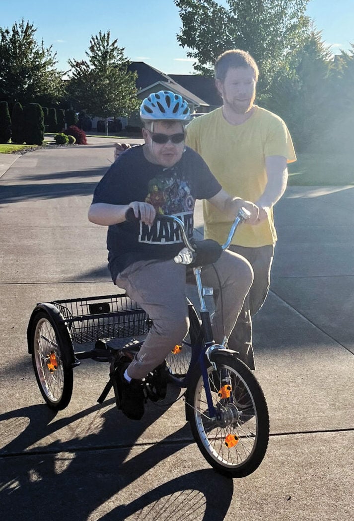 Jim riding a bike with a staff member.