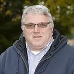board member tom thweatt wearing glasses, jacket, glasses, looking at the camera