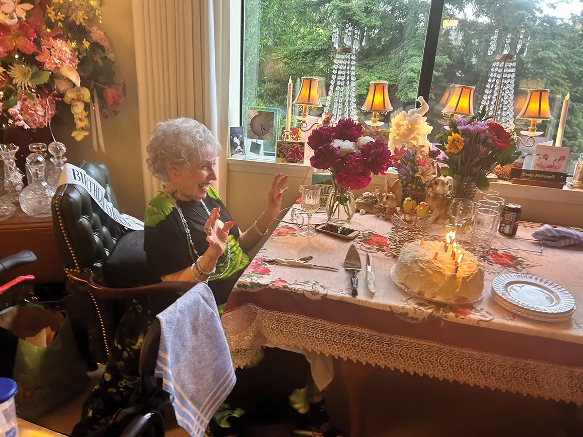 Betty celebrating her birthday. Cake on the table. Smiling.