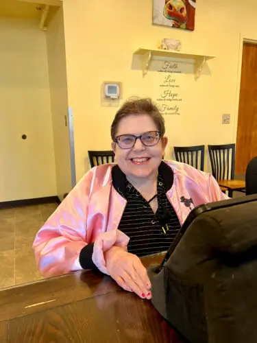 Cascade Christian Home - A lady wearing a pink jacket, sitting down and smiling.