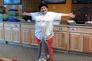 A woman spreading her arms in front of a vaccume, at a workplace.