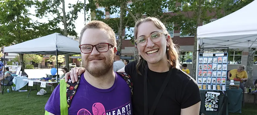 a woman and a man smiling. man wearing glasses. at a park.