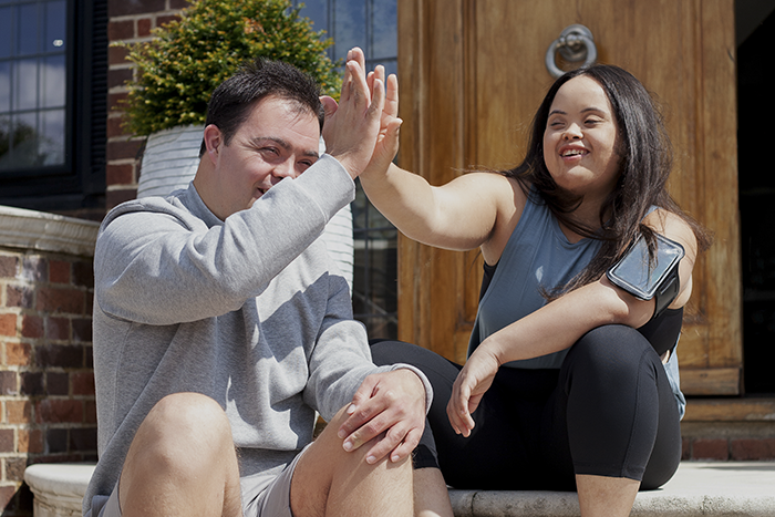 a man and a woman doing high-five, sitting, smiling
