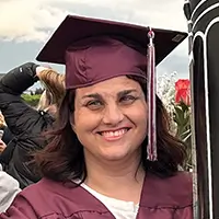 Hilary wearing a purple graduation cap and smiling.