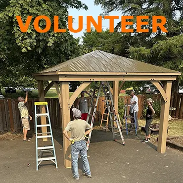 text says volunteer. five volunteers working on building a gazebo